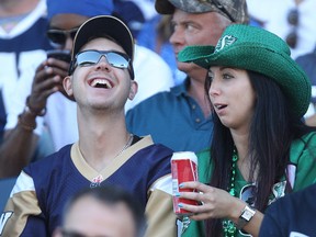 Fans sporting Winnipeg Blue Bombers and Saskatchewan Roughriders jerseys chat during CFL action in the Banjo Bowl at Investors Group Field in Winnipeg, Man., on Sun., Sept. 7, 2014.