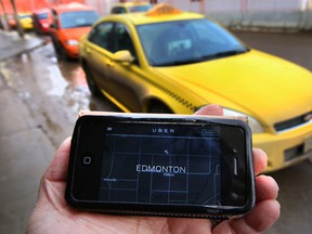 Phone app with Uber website in front of a line up of taxis at the downtown bus station in Edmonton, Alta. on Friday, Feb. 13, 2015. Perry Mah/Edmonton Sun/QMI Agency