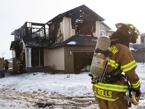 An Edmonton Fire Rescue Service firefighter is seen as firefighters battle a blaze at 8387 Shaske Crescent in Edmonton, Alta., on Friday, Feb. 13, 2014. Six trucks battled the blaze, which was called in before 9:30 a.m. Ian Kucerak/Edmonton Sun