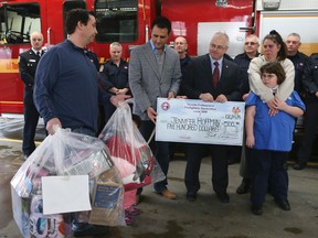 Jennifer Hoffman and her nine-year-old daughter Samantha receive a cheque and gifts from the Toronto Professional Fire Fighters' Association on Feb. 14, 2015. Councillor Justin DiCiano, Ward 5, was on hand, left, with Damien Walsh, vice-president of the TPFFA presenting the cheque. (Veronica Henri/Toronto Sun)