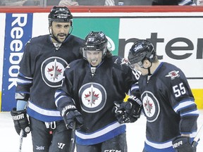 Mathieu Perreault is helped off the ice after being injured in Monday's game. (BRIAN DONOGH/Winnipeg Sun)
