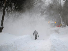 A man walks near a snow plow after a winter storm hit Charlottetown, Prince Edward Island February 16, 2015. Canadian media reported that 80 cm (2.6 feet) of snow hit the province, breaking a single storm record. REUTERS/Nathan Rochford