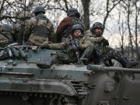 Ukrainian servicemen ride on a military vehicle near Artemivsk on Feb. 19, 2015. Fighting raged in eastern Ukraine on Thursday despite European efforts to resurrect a still-born ceasefire, a day after pro-Russian separatists who spurned the truce forced thousands of government troops out of a strategic town. (REUTERS/Gleb Garanich)