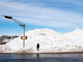 A pedestrian walks past a mountain of snow in Halifax on Tuesday Feb. 17, 2015. (Scott Blackburn/QMI Agency)