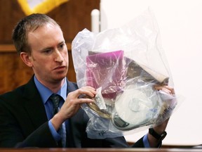 Timothy Woods of the Mass. State Police Forensics Laboratory examines an evidence bag containing a scale and dish during the murder trial of former NFL player Aaron Hernandez at the Bristol County Superior Court in Fall River, Massachusetts, February 19, 2015. (REUTERS/Charles Krupa/Pool)