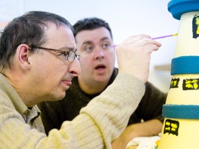 Day program assistant Shawn Bates watches as client Jim McGeough paints windows onto a handmade lighthouse sculpture at L?Arche London, a day program for adults with intellectual disabilities, at Byron United Church in London Thursday. (CRAIG GLOVER, The London Free Press)