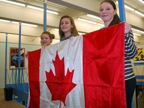 Parkside Collegiate Institute students Amanda Sawyer, left, Victoria Anglan and Sophia Watson hold a Canadian flag in the school library. They're headed to Ottawa Sunday for the week-long Forum for Young Canadians, a national program that gives students an up-close look at how government works. (Ben Forrest/Times-Journal)