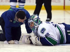 Canucks goalie Ryan Miller is tended to after being injured in the second period of Vancouver's 4-0 win over the Islanders on Sunday in Uniondale, N.Y. (Brad Penner/USA TODAY Sports)