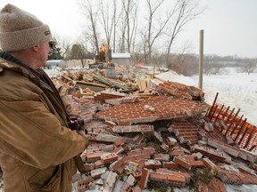 David Shuttleworth watches as a large excavator demolishes their retirement dream home outside of Delaware west of London, Ont. on Tuesday February 17, 2015.