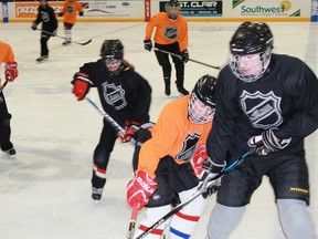 Players from Equipe Orange and Equipe Noir fight for the puck during Conseil Scolaire Catholique Providence's hockey tournament which took place at the RBC Centre on Feb. 24.