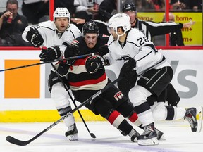 Ottawa Senators' Mark Stone gets checked by Los Angeles Kings' Robyn regehr (L) and Jaret Stoll during NHL hockey action at the Canadian Tire Centre in Ottawa, Ontario on Thursday December 11, 2014. Errol McGihon/Ottawa Sun/QMI Agency