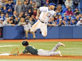 Brett Lawrie, making a leaping catch of an off-target throw as Coco Crisp slides into third with a stolen base last season, is now teammates with the Oakland Athletics base-runner following November’s blockbuster trade with the Blue Jays. (DAN HAMILTON, USA Today Sports)