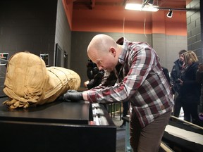 Royal Ontario Museum preparators Myles Zarowny (pictured)and Aurora Hall position 3,000-year-old mummy Nefer-Mut into place at Dynamic Earth in Sudbury, Ont. on Wednesday. Gino Donato/Sudbury Star/QMI Agency