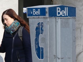 A woman uses a mobile device while walking past a Bell payphone in Ottawa February 19, 2014. 
REUTERS/Chris Wattie