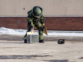 A member of the RCMP's explosives disposal unit sets up equipment to test a suspicious package that was found on Thursday February 26, 2015 in Whitecourt, Alta. A section of the parking lot next to Humpty's restaurant in the town's west end, where the object was located, was cordoned off while officers examined it. An RCMP officer opened the object and removed it shortly after 5 p.m. Adam Dietrich/Whitecourt Star/QMI Agency