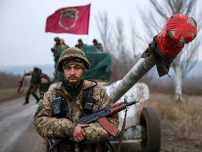 A member of the Ukrainian armed forces stands guard as a convoy of the Ukrainian armed forces including armoured personnel carriers, military vehicles and cannons prepare to move as they pull back from the Debaltseve region, in Paraskoviyvka, eastern Ukraine, February 26, 2015. Ukrainian troops towed artillery away from the front line in the east on Thursday, a move that amounted to recognising that a ceasefire meant to take effect on Feb. 15 was holding at last.  REUTERS/Gleb Garanich