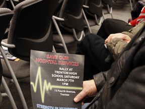 A supporter of Trenton Memorial Hospital (TMH) holds a flyer advertising a rally in support of TMH organized by the "Our TMH" group slated for Saturday, March 7, while MPP of Northumerland-Quinte West Lou Rinaldi, top, announces $3.5 millions in support to Quinte Health Care (QHC), including TMH, during a press conference at Quinte West city hall in Trenton, Ont. Friday, Feb. 27, 2015.  - JEROME LESSARD/THE INTELLIGENCER/QMI AGENCY