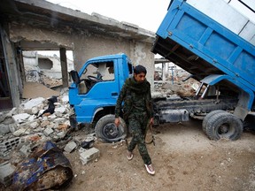 A fighter of the Kurdish People's Protection Units (YPG) walks in the northern Syrian town of Kobani January 30, 2015. Sheets meant to hide residents from snipers' sights still hang over streets in the Syrian border town of Kobani, and its shattered buildings and cratered roads suggest those who fled are unlikely to return soon. Kurdish forces said this week they had taken full control of Kobani, a mainly Kurdish town near the Turkish border, after months of bombardment by Islamic State, an al Qaida offshoot that has spread across Syria and Iraq. (REUTERS/Osman Orsal)