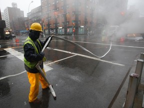 A worker pulls a hose to a drain as he works to pump out a manhole on 7th Avenue in Manhattan in this Aug. 28, 2011 file photo. (REUTERS/Mike Segar)