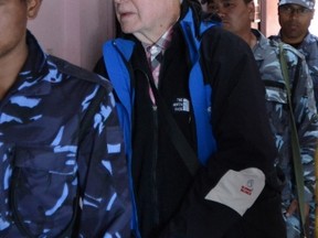 Canadian national Ernest Fenwick MacIntosh, accused of sexually abusing a Nepalese child, is escorted by police for his appearance at the District Court in Lalitpur on February 5, 2015.  AFP PHOTO / PRAKASH MATHEMA