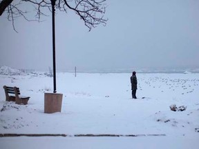 A man stands in falling snow at the shore of the Hudson River in the New York City suburban town of Nyack, New York March 1, 2015.   REUTERS/Mike Segar