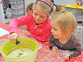 Izzy Robinson (left), uses yellow paint to create some unique artwork, while sister Rya looks on, last Thursday, Feb. 26, at the West Perth Public Library.'s Tweenie Tots program. KRISTINE JEAN/MITCHELL ADVOCATE