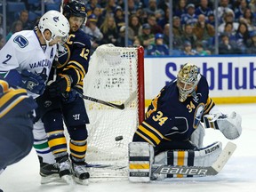 Vancouver Canucks defenseman Dan Hamhuis tries to jam the puck past Buffalo Sabres goalie Michal Neuvirth as right winger Brian Giontadefends during the third period at First Niagara Center on Feb. 26, 2015. (Kevin Hoffman/USA TODAY Sports)