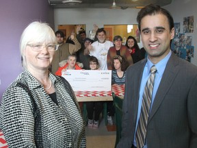 With students and staff of the H'art Centre in the background, executive director Katherine Porter, left, and Queen's MBA student Saad Ahmad meet for the presentation of a $10,000 to the centre from the MBA program. (Michael Lea/The Whig-Standard)