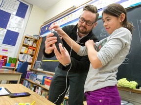 Steve Jones, a Western University clinical audiology masters student, helps Maria Saavedra determine the volume of music coming through headphones using a sound level meter as he talks to Susan Vuylsteke?s Grade 4 class at St. John Catholic French Immersion school Monday. (CRAIG GLOVER, The London Free Press)