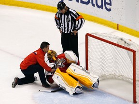 Florida Panthers trainer David Zenobi attends to injured goalie Roberto Luongo as referee Justin St. Pierre looks on in the first period Tuesday at BB&T Center. (Robert Mayer/USA TODAY Sports)