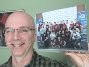 Michael Bird, a parent volunteer on the robotics team at Frontenac Secondary School, holds a photo of last year's team. This year's team is holding a fundraising dinner Fri., Mar. 6 at their school to help pay for supplies and transportation costs to competitions. (Michael Lea/The Whig-Standard)
