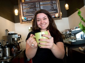 Fire Roasted Coffee barista Caroline Bloss holds out a cup of coffee at the Wortley Rd. coffee shop, where a small safe containing cash was stolen Thursday morning. (CRAIG GLOVER, The London Free Press)