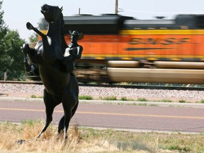 A Burlington Northern Santa Fe (BNSF) train rolls by a statue of the state symbol of the state of Wyoming, a bucking bronco, in Ft. Laramie, Wyoming July 15, 2014. (REUTERS/Rick Wilking)