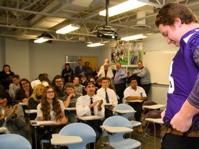 Offensive lineman Dylan Giffen, all 6-foot-9 and 320 pounds of him, pulls on a Mustangs football jersey with the help of head coach Greg Marshall during the ceremony for the class of 2015 recruits at Western on Thursday night. (MIKE HENSEN, The London Free Press)