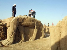 Iraqi workers clean a statue of a winged bull at an archeological site in Nimrud in this July 17, 2001 file photo. Islamic State has begun bulldozing the ancient Assyrian city of Nimrud in Iraq, the government said. (AFP PHOTO/Karim Sahib)