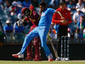 India’s Ravichandran Ashwin (right) attempts to field the loose ball with his feet off West Indies batsman Jonathan Carter during their Cricket World Cup match in Perth yesterday. India won by four wickets.  (Reuters)