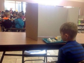 A first-grader eats alone behind a cardboard wall as his punishment for being late. The boy's grandmother, Laura Lucas Hoover, posted this picture on Facebook. 
(Photo from Facebook)