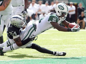 New York Jets running back Chris Johnson (21) scores a touchdown despite the efforts of Oakland Raiders safety Charles Woodson during NFL play at MetLife Stadium. (Brad Penner/USA TODAY Sports)