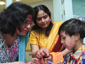 Madhu Mehan, left, and Shubha Mekherjee let five-year-old Sidd Kumari put some colour on their faces during the Hindu Temple of Kingston's Holi Celebrations at Cataraqui Woods Elementary School in Kingston on Saturday. (Julia McKay/The Whig-Standard)