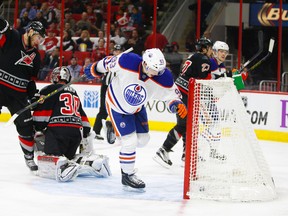 Forward Ryan Nugent-Hopkins scores gets the puck past Carolina Hurricanes netminder Cam Ward and forward Jordan Staal at Raleigh’s PNC Arena. Despite his hat trick, the Oilers fell 7-4 with returning goalie Richard Bachman in net. JAMES GUILLORY/USA Today Sports