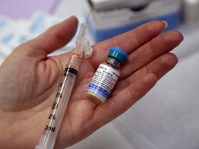 Public health nurse Debbie Abbott holds a bottle of the combined vaccine for measles, mumps and rubella at Hastings Prince Edward Public Health in Belleville, Ont., in this Feb. 10, 2015 file photo. (Luke Hendry/QMI Agency)