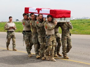 Pallbearers from the Canadian Special Operations Regiment (CSOR) carry the casket of their fallen comrade during the ramp ceremony at Erbil International Airport in Iraq Sunday, March 8, 2015. - DND HANDOUT