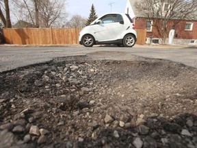 A Smart car passes by a pothole on Selwyn Ave. - a side street in East York east of St. Clair and O'Connor Aves. (Jack Boland/Toronto Sun files)