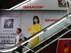 A man rides an escalator past Sharp Corp's advertisements at an electronics retail store in Tokyo in this Oct. 31, 2013 file photo. REUTERS/Toru Hanai/Files
