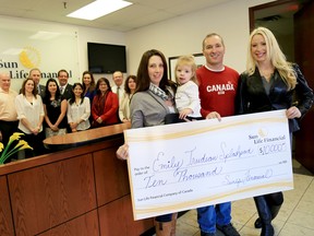 Emily Mountney-Lessard/The Intelligencer 
Angela Trudeau, with one-and-a-half-year-old Kendall, and Angela's brother-in-law, Shawn, accepts a Sun Life Financial donation of $10,000 from Taryl Kramp, financial centre manager in Belleville, Tuesday. The money is slated for the Emily Trudeau Splash Pad project.