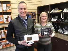 Brian McKenzie, left, regional director of the Canadian Hearing Society, and Debbie Martin, manager of administration and support services, stand in the CHS office in Kingston, holding alerting devices available to the deaf and hearing impaired. The society is celebrating its 75th anniversary on Wednesday. (Michael Lea/The Whig-Standard)