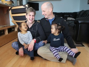 Johanne and Michael Wagner sit with their twin daughters Binh, left, and Phuoc, in the family's home in Kingston.
(Elliot Ferguson/The Whig-Standard)