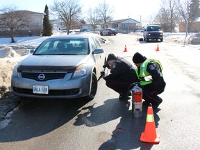 Woodstock Police take photos at the scene of a collision in southeast Woodstock, where two pedestrians were struck and injured by a car early Wednesday morning. (Megan Stacey/Sentinel-Review)