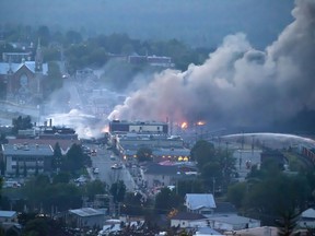 In this July 6, 2013 file photo, firefighters douse blazes after a freight train loaded with oil derailed in Lac-Megantic in Canada's Quebec province, sparking explosions that engulfed about 30 buildings in fire. (AFP PHOTO/Francois Laplante-Delagrave)