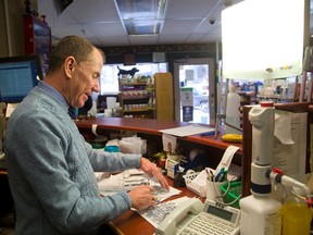 Jeff Robb of Turner Drugs in Old South works under a bright light that mimics sunlight at his store. (MIKE HENSEN, The London Free Press)